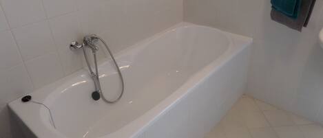 A white bathtub with a handheld showerhead, a towel rack with a blue towel, and a white sink.