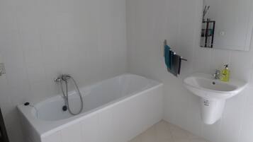 A bathroom with a bathtub, a sink, and a mirror.
