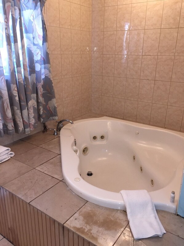 A bathroom with a freestanding bathtub, tiled walls, and a curtain with a floral pattern.