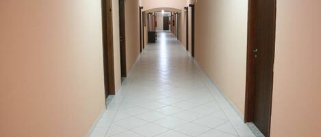 A long, narrow hallway with doors on both sides, leading to individual rooms.