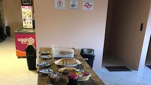 Une table de buffet avec divers plats et ustensiles, une poubelle et un panneau indiquant les toilettes sur le mur.