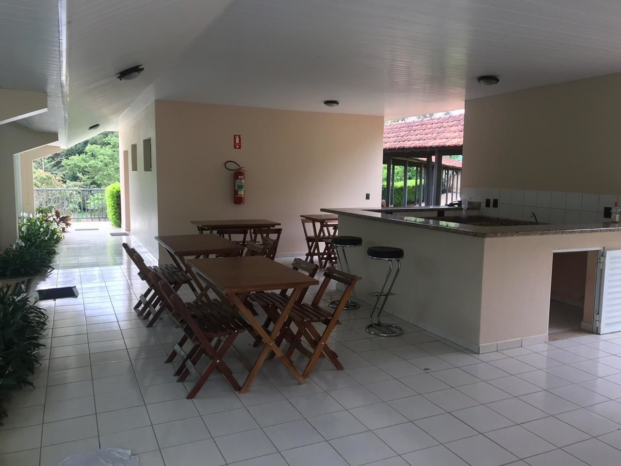 Un espacio interior amplio con una mesa larga y sillas, una pequeña zona de cocina con mostrador, y un extintor de incendios en la pared.