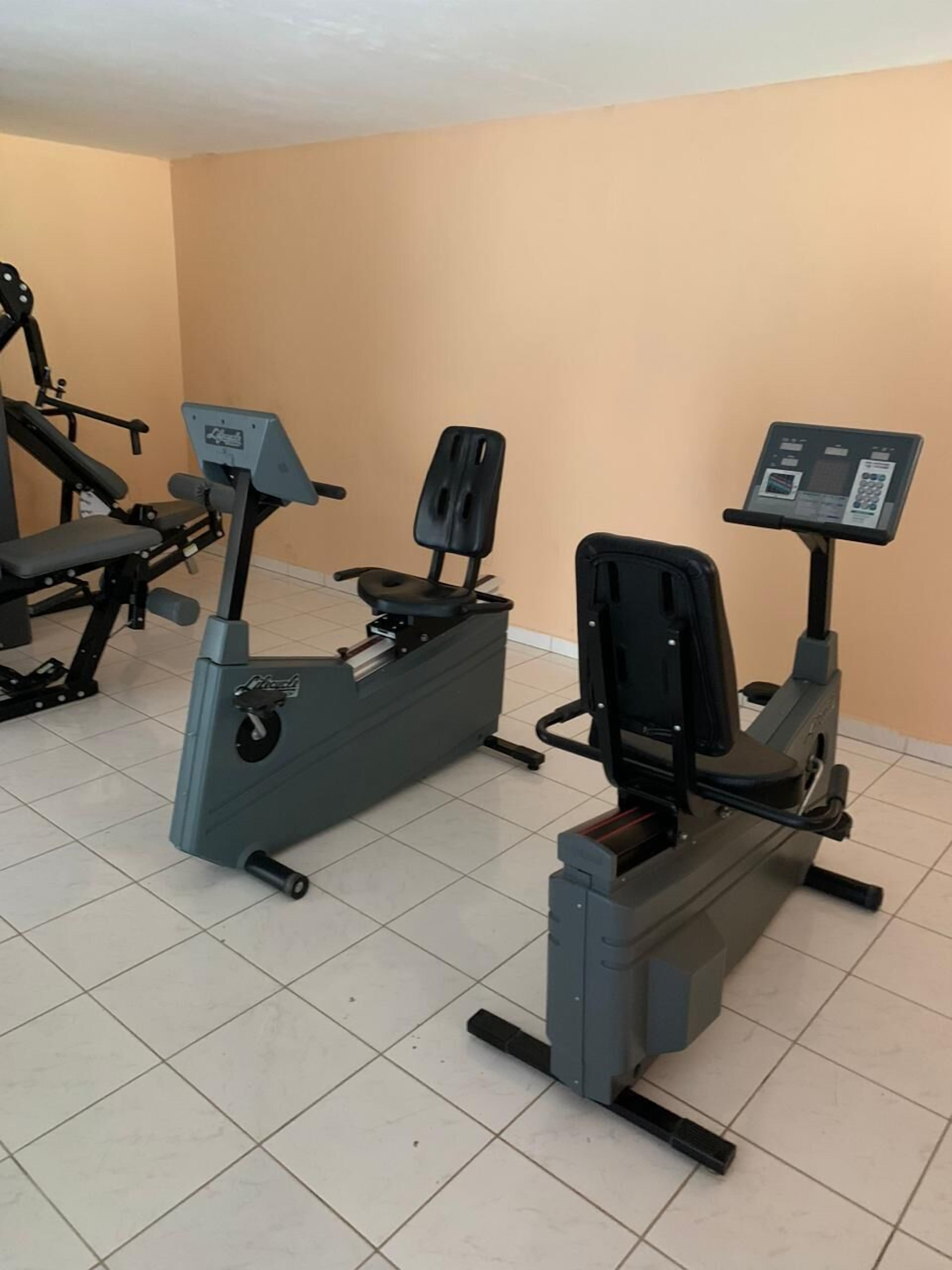 Et fitnesscenter med træningsmaskiner, herunder en motionscykel og et løbebånd.