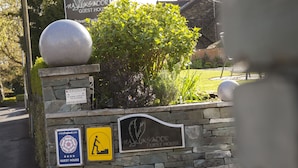 A stone wall with a sign for the Hawksmoor Guest House, a warning sign for a closed circuit television, and a sign for enjoyEngland.com.