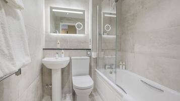 A modern bathroom with a sink, toilet, and bathtub.