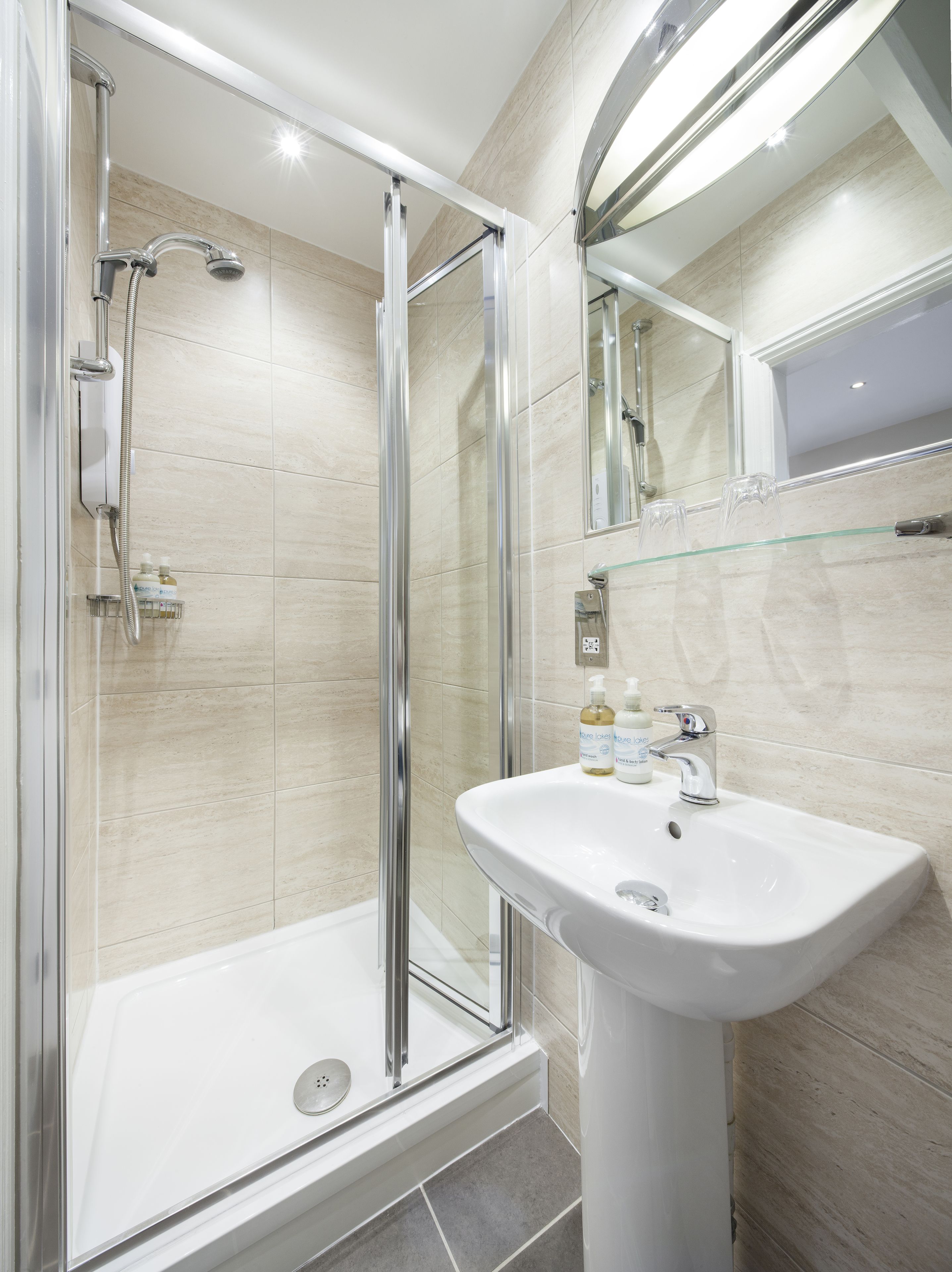 A modern bathroom with a glass-enclosed shower, a white sink, and a mirror above it.