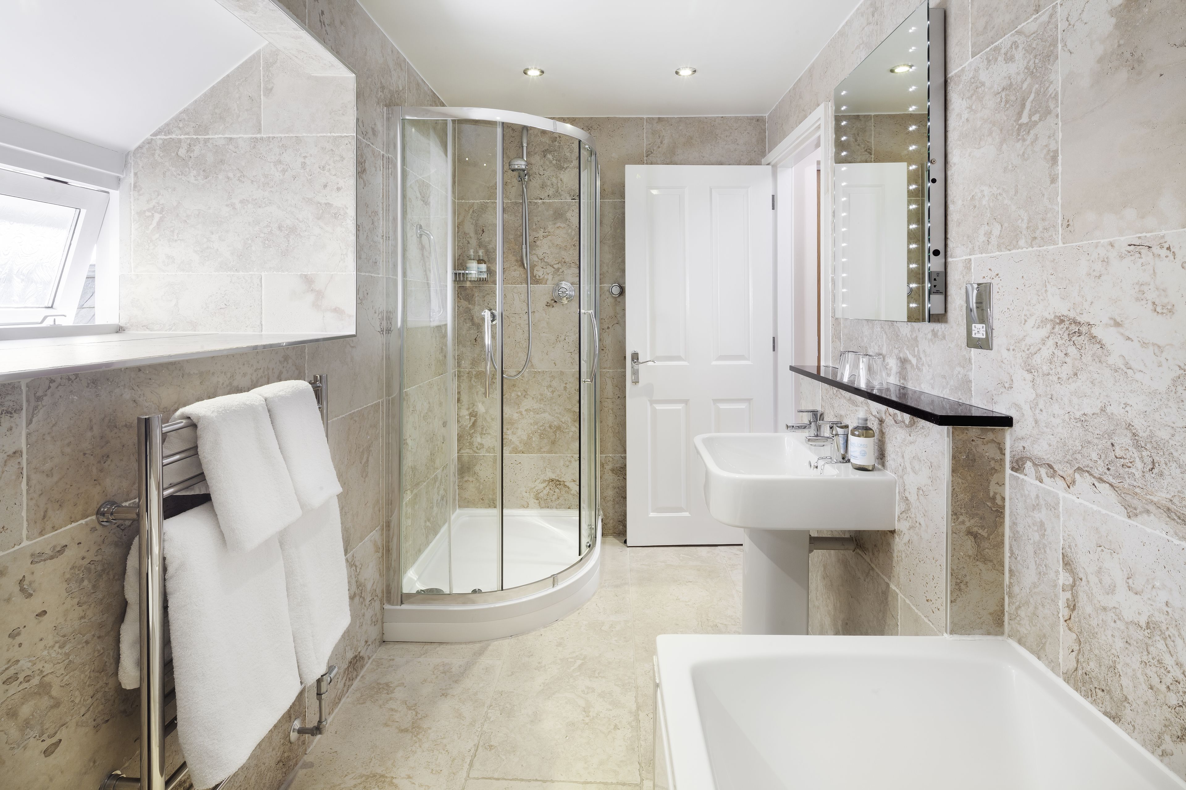 A modern bathroom with a glass-enclosed shower, a white sink, and a large bathtub.