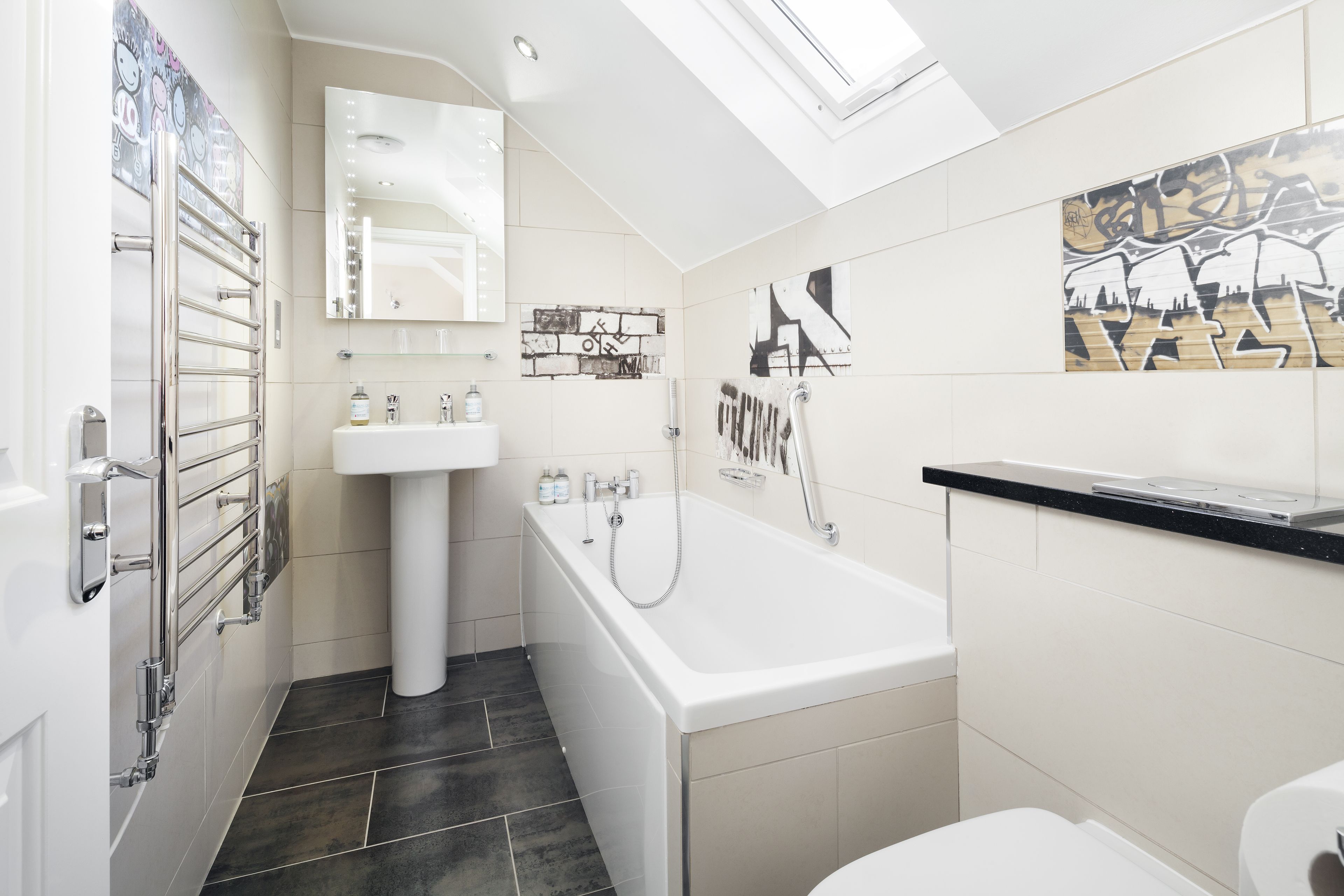 Une salle de bain moderne avec un puits de lumière, une baignoire, un lavabo et des toilettes.