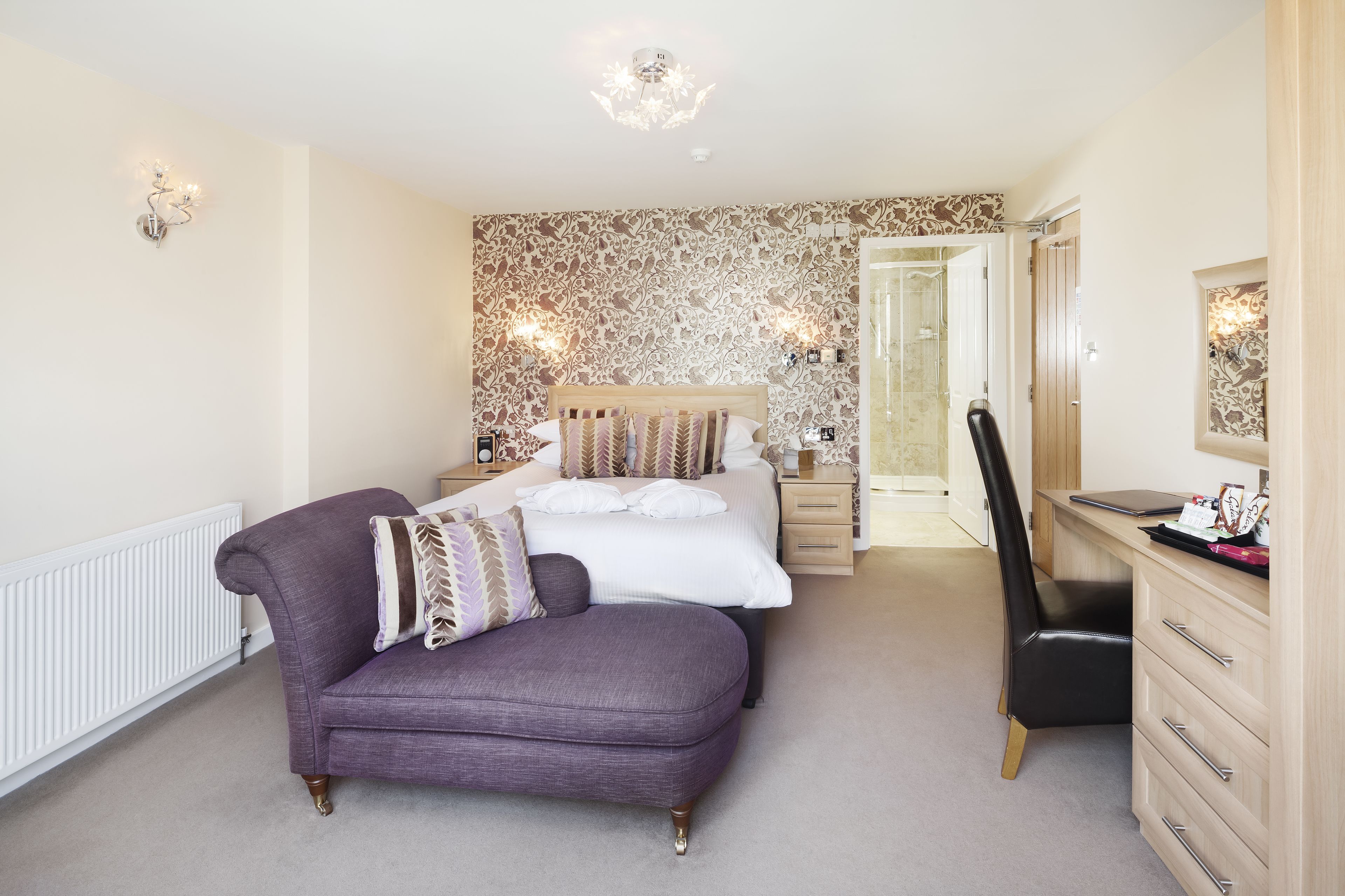A bedroom with a bed, a chair, a dresser, and a desk.