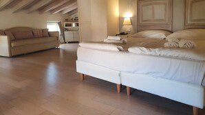 Een ruime kamer met een groot bed, een bank en een bureau.