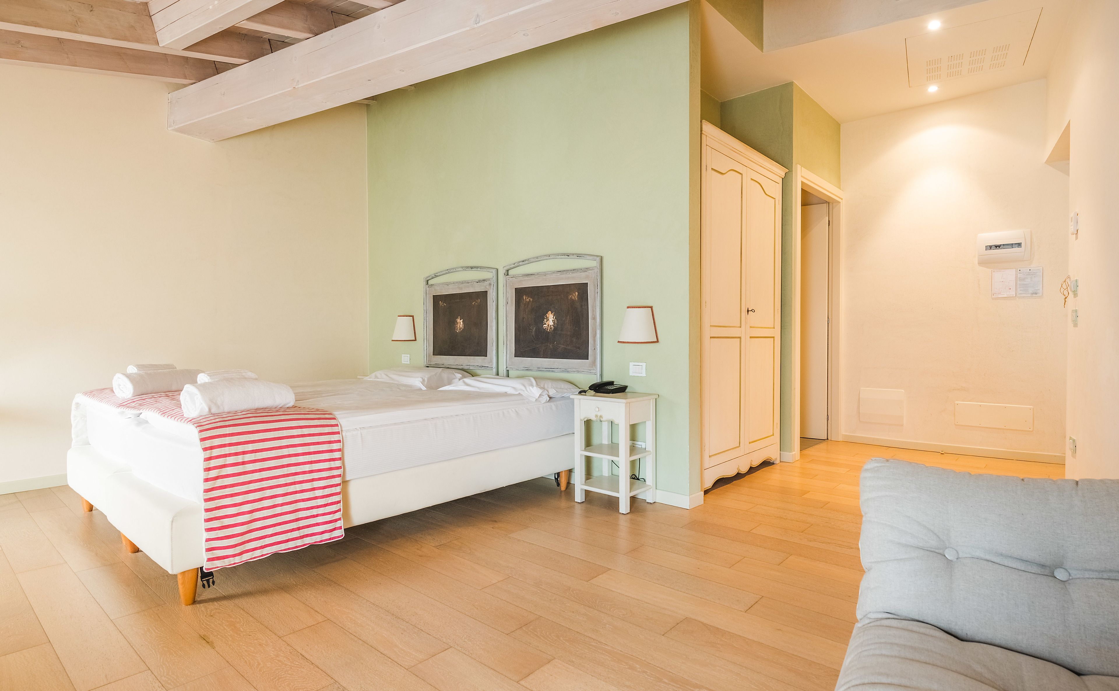 A bedroom with a bed, bedside tables, a wardrobe, and a sofa.