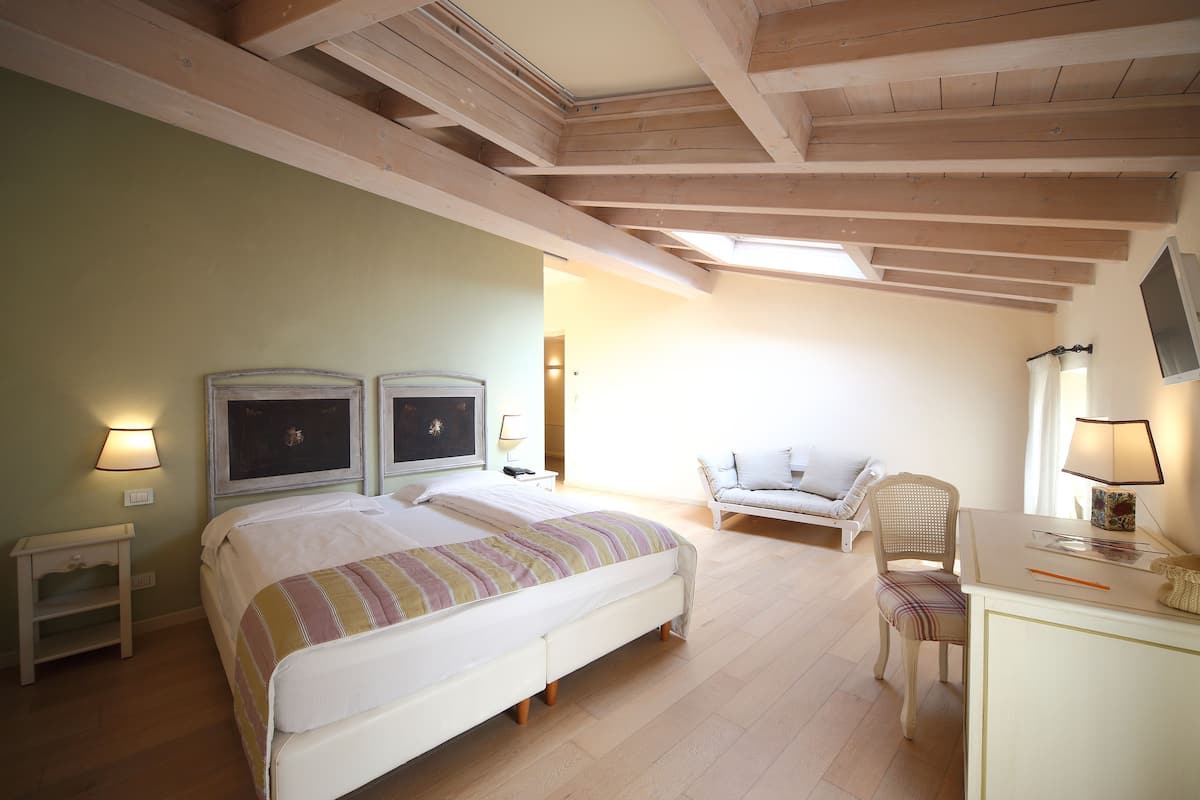A bedroom with a bed, two bedside tables, a chair, and a desk with a lamp.