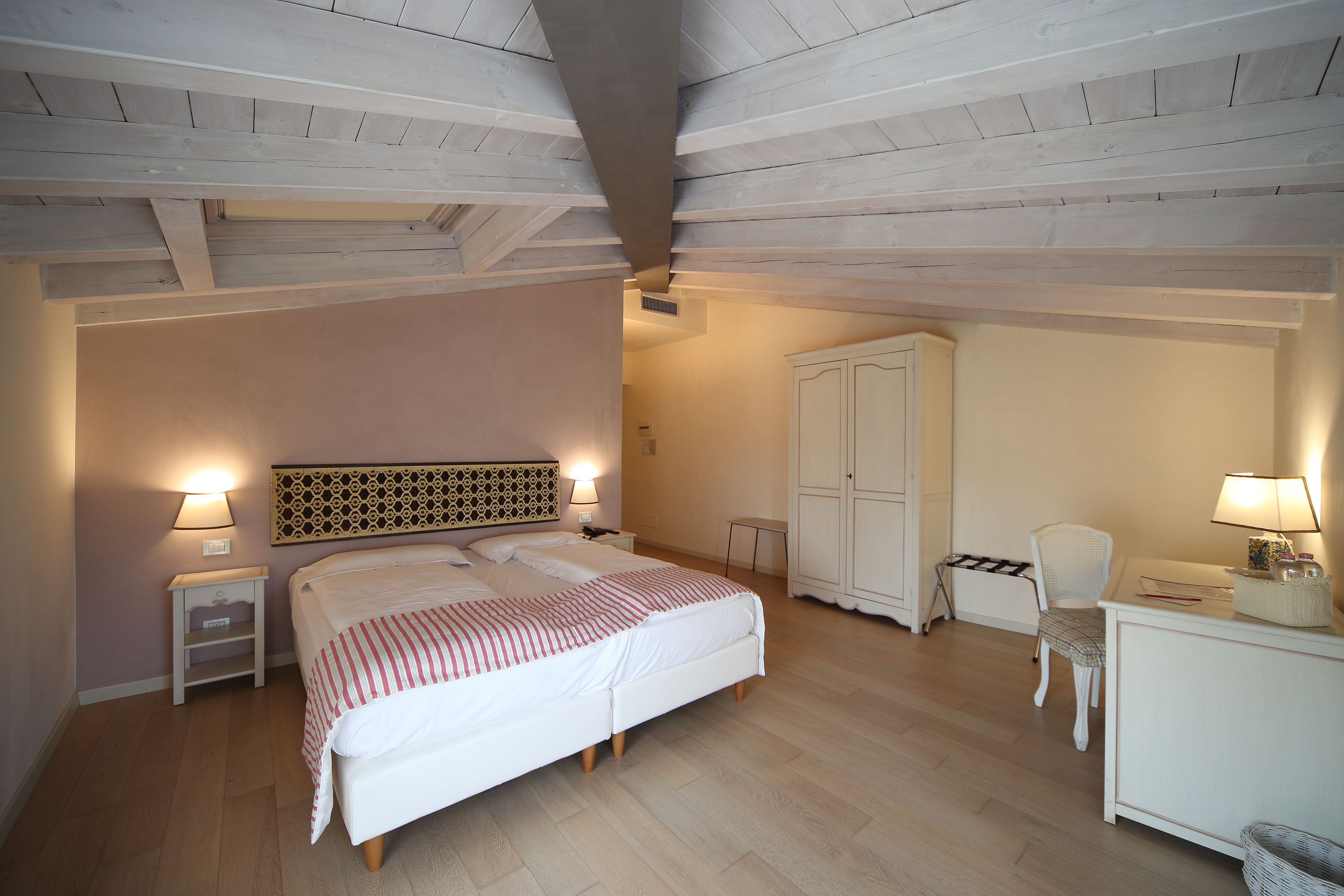 A bedroom with a bed, bedside tables, a wardrobe, a desk, and a chair.