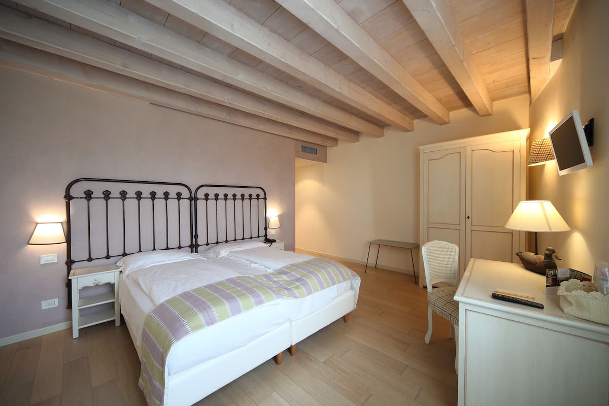 A bedroom with a bed, bedside tables, a chair, a desk with a lamp, and a wardrobe.