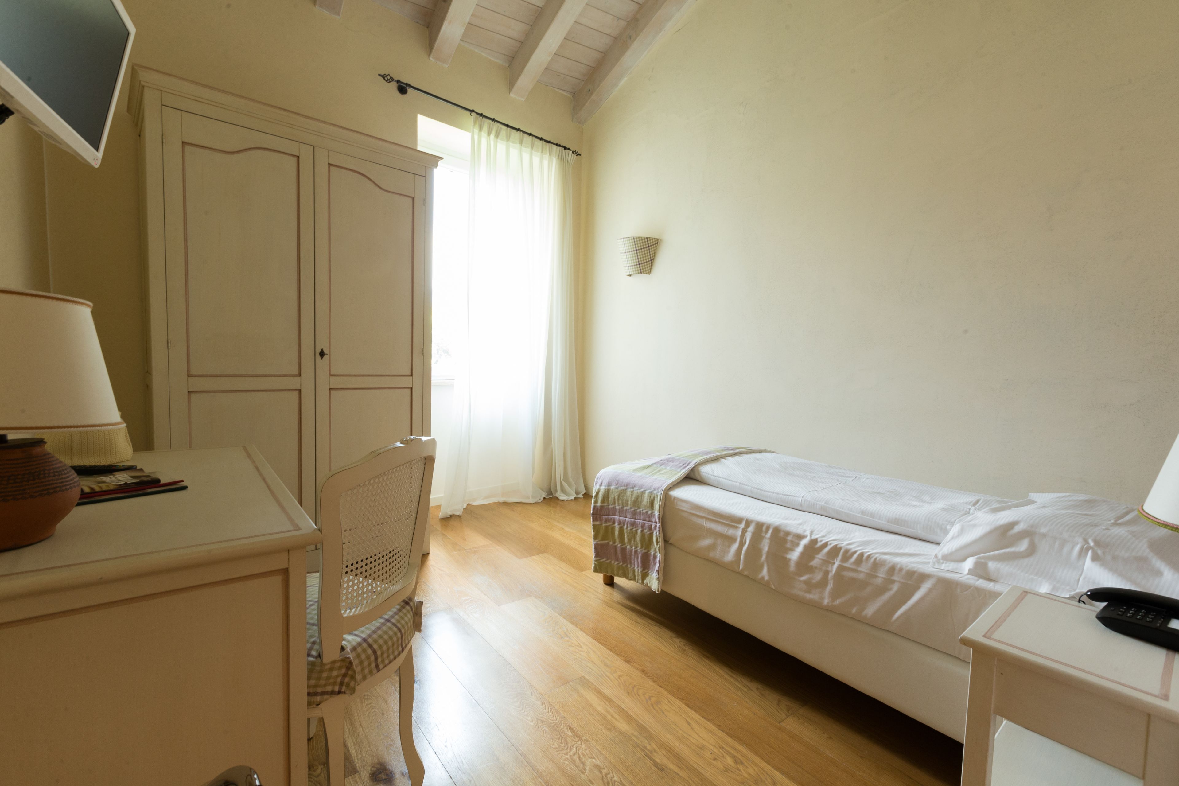 Ein Schlafzimmer mit Bett, Schreibtisch, Stuhl, Lampe und Nachttisch.