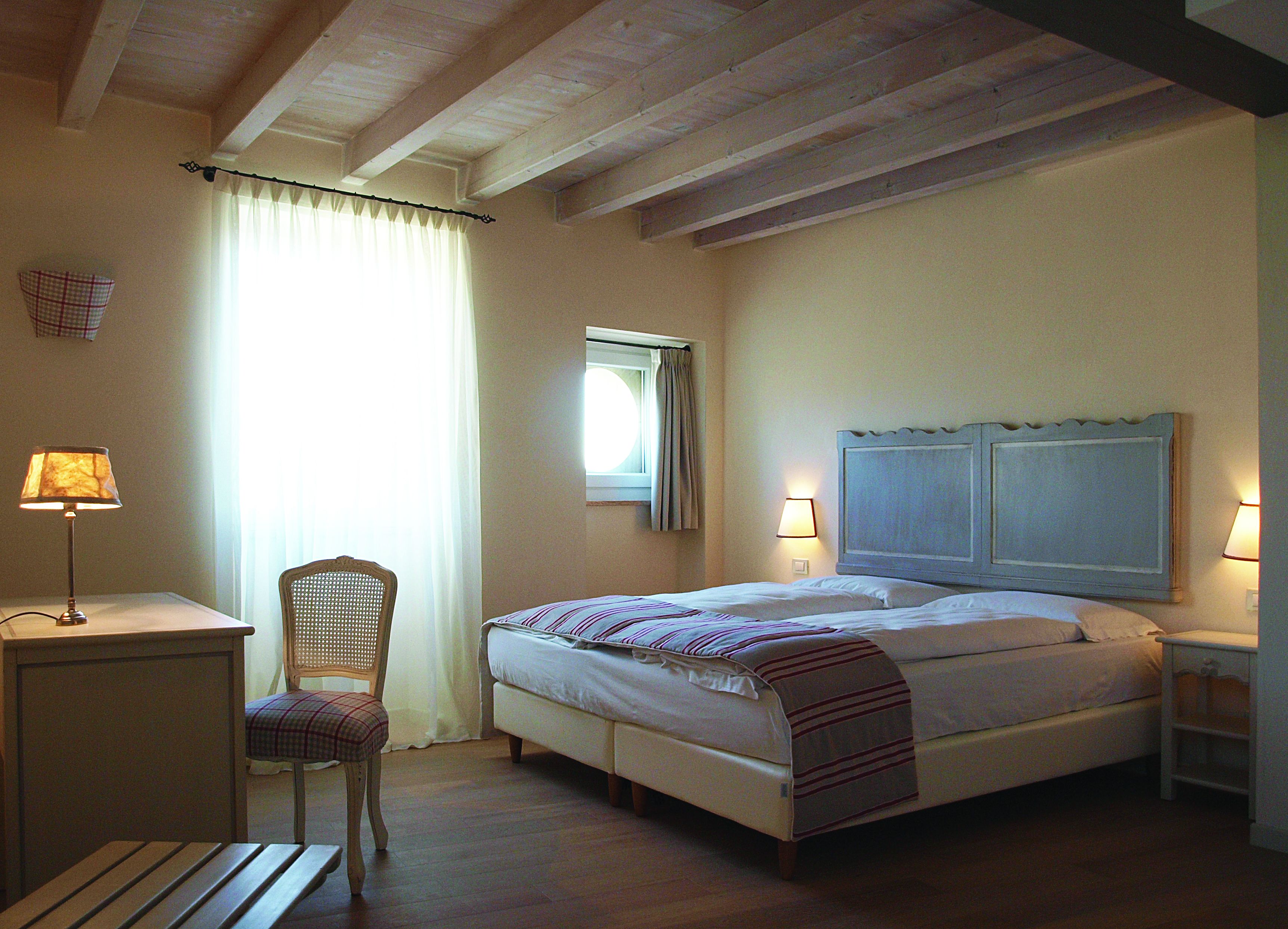 Quarto com cama, mesas de cabeceira, escrivaninha e cadeira.