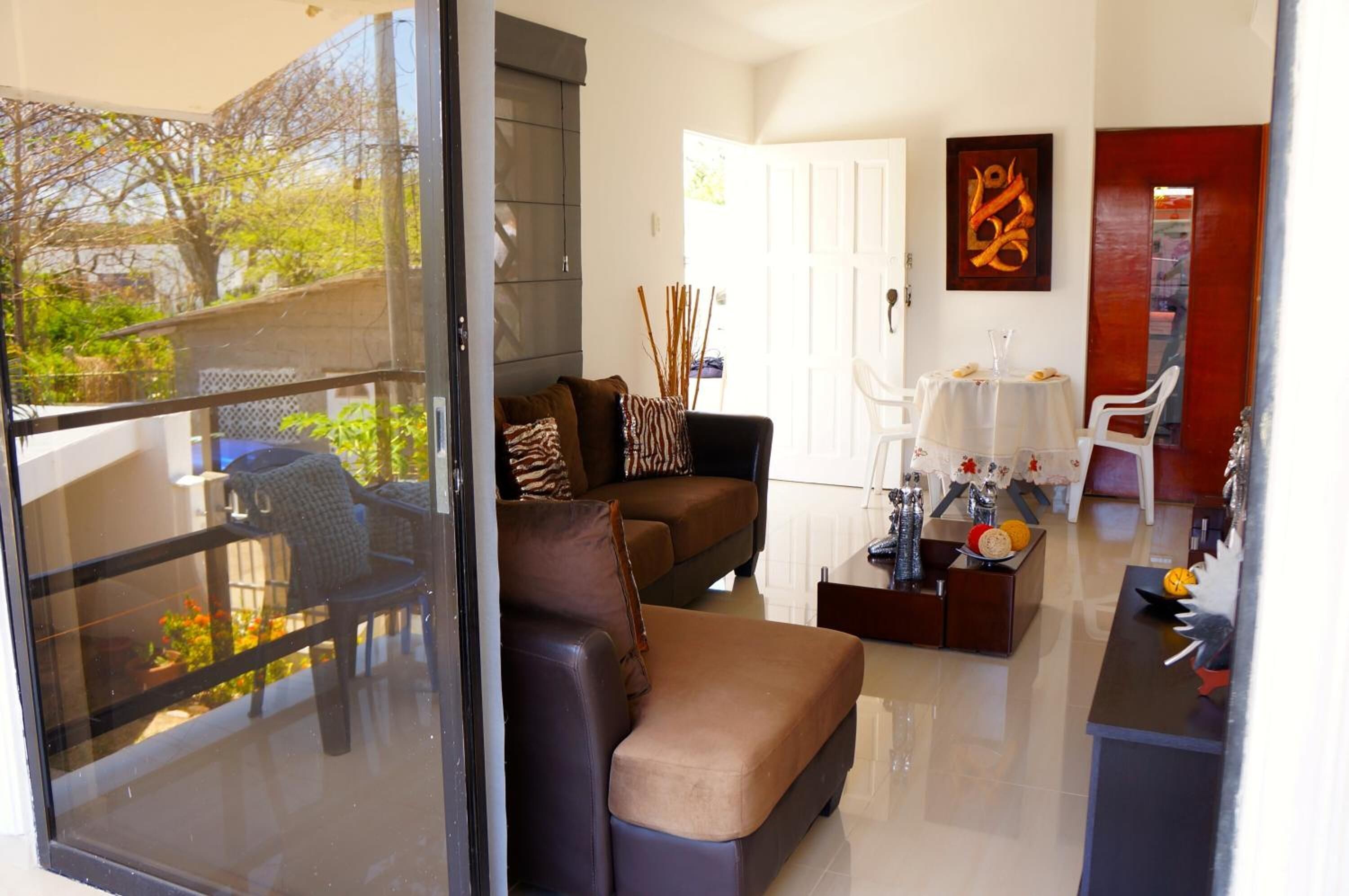 A modern living room with a sofa, coffee table, and a dining area with a table and chairs.