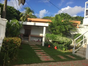 A residential area with a paved pathway leading to a house with a brick entrance and a small porch. - Posada Vasquez Oviedo (San Andrés)