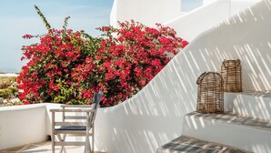 A white outdoor seating area with a chair, a small table, and wicker lanterns. - Ploes Seaside Houses (Naxos)