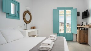 A hotel room with a bed, a desk, a TV, and a view of the outside. - Ploes Seaside Houses (Naxos)