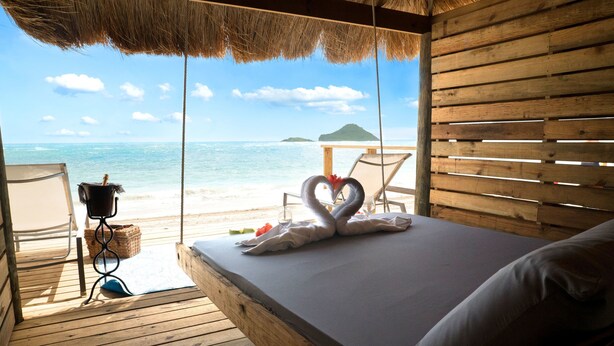 Un terrazzo in legno con un letto e vista sulla spiaggia.