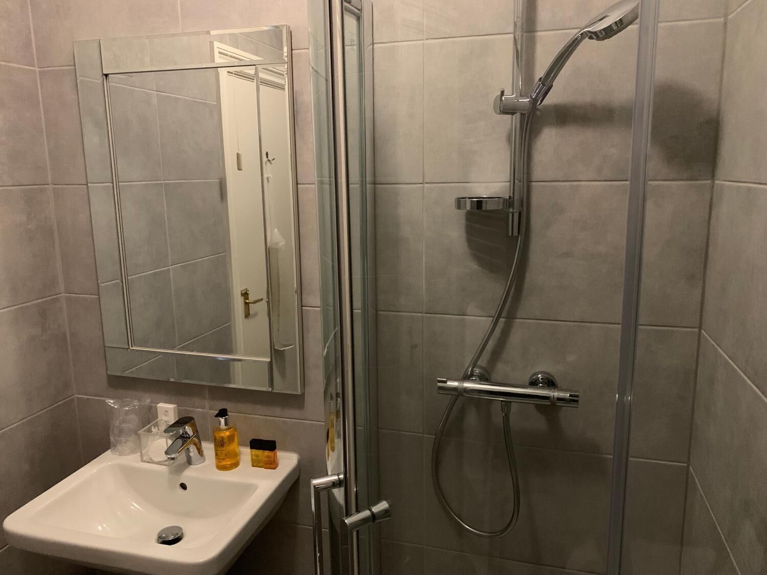 Une salle de bain avec une douche à parois de verre, un lavabo blanc et un miroir au-dessus.