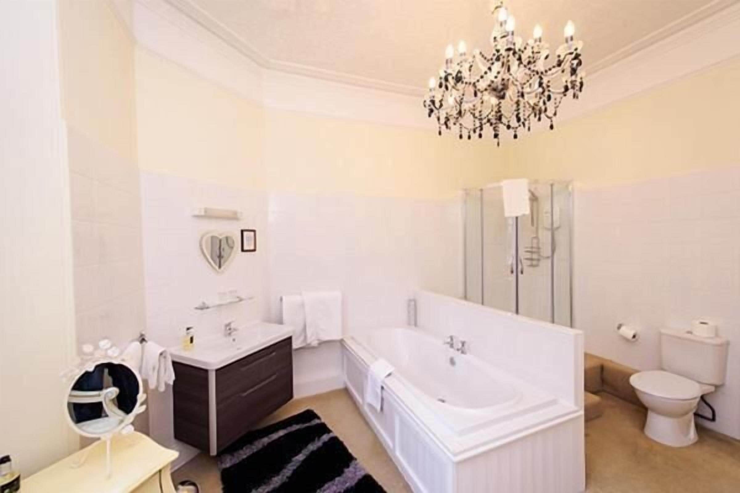 Un baño moderno con una bañera grande, un lavamanos con espejo y un inodoro.