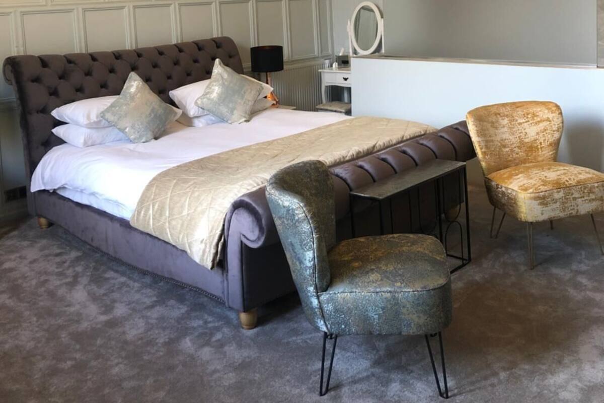 A bedroom with a large bed, a desk, and a chair.
