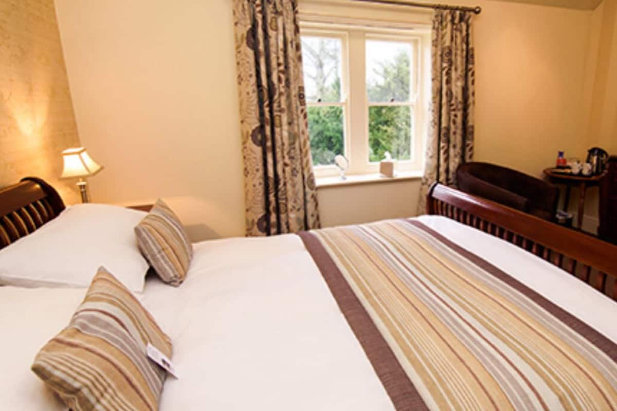 A hotel room with a bed, a dresser, a television, and a window with curtains.