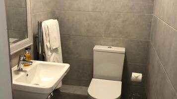 A small, modern bathroom with a white sink, toilet, and mirror.