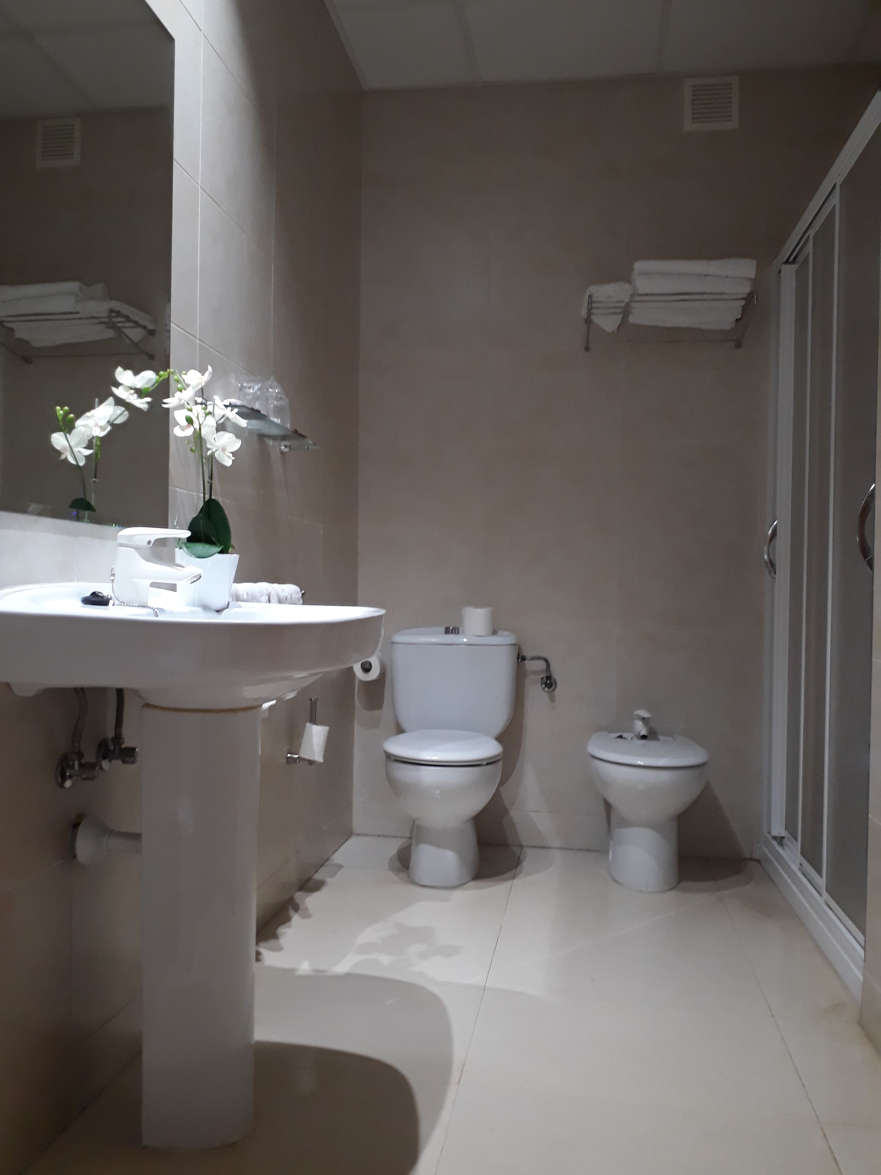 Un baño con lavamanos, inodoro, bidé y un espejo.