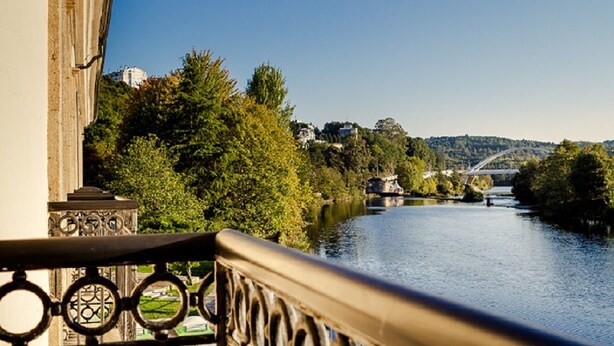 A river with a bridge in the background, surrounded by trees and buildings. - Hotel Balneario de Lugo (Lugo)