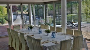 A dining area with a long table set for a meal, surrounded by chairs with white covers. - Hotel Balneario de Lugo (Lugo)