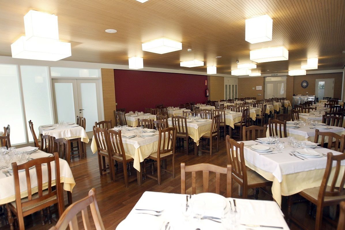Un amplio comedor con numerosas mesas y sillas dispuestas en filas.