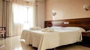 A hotel room with two beds, a wooden headboard, a nightstand, a lamp, and a window with curtains. - Hotel Balneario de Lugo (Lugo)