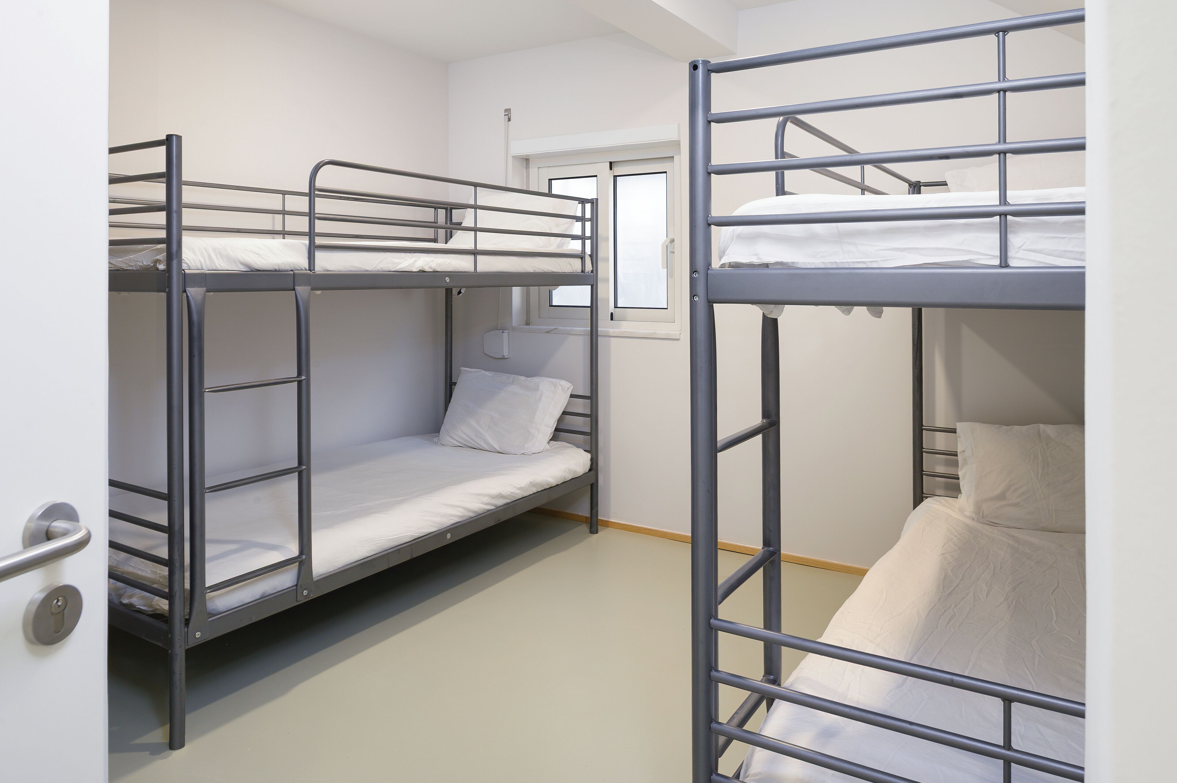 A bunk room with two bunk beds, a window, and a door.