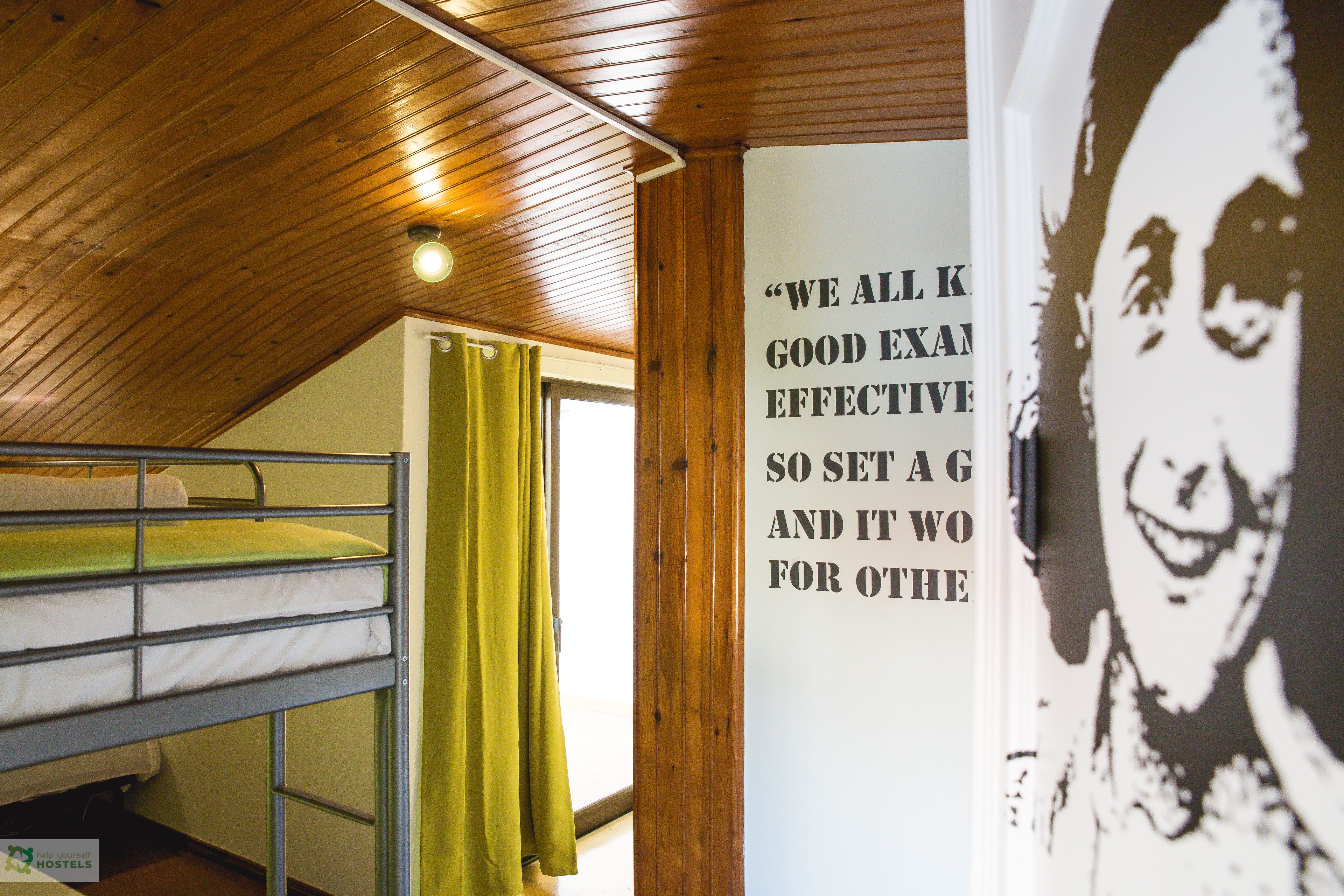 Dormitorio con literas, un cartel en la pared y techo de madera.