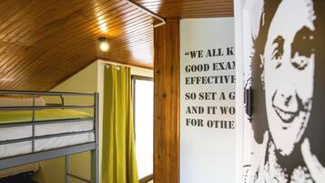 Dormitorio con literas, un cartel en la pared y techo de madera.