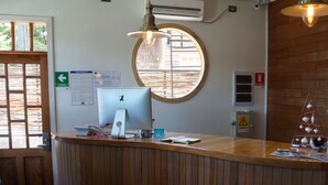 A reception desk with a computer, a fire extinguisher, and a warning sign on the wall. - Hotel Boutique Refugio de Navegantes (Dalcahue)