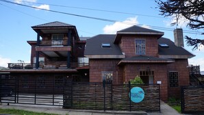 A two-story building with a balcony on the upper level, a fenced entrance, and a sign indicating a nautical theme. - Hotel Boutique Refugio de Navegantes (Dalcahue)