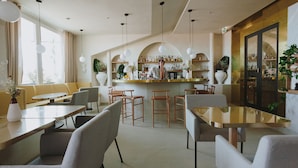 A modern restaurant with a bar area, seating arrangements, and a view of the outdoors.