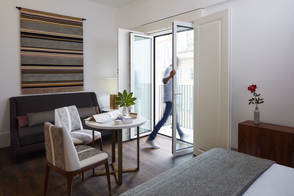 Una camera d'albergo moderna con un letto, un divano, un tavolo da pranzo e un balcone.