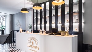 A reception desk with a logo, a checkered floor, and a modern interior with pendant lighting and a plant.