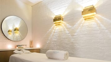 Ein Hotelzimmer mit weißer Backsteinwand, einem runden Spiegel und zwei Wandleuchten.