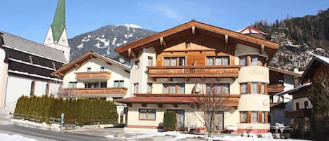 Un edificio de varios pisos con estilo arquitectónico alpino tradicional, que cuenta con balcones y una entrada destacada.