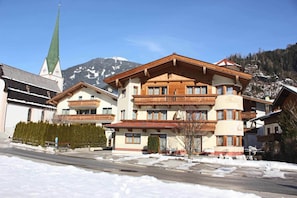 A multi-story building with a traditional Alpine architectural style, featuring balconies and a prominent entrance.