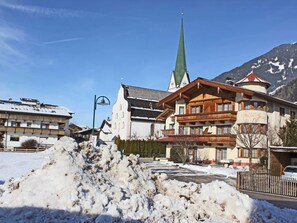 Un hotel de estilo arquitectónico alpino tradicional, con una imponente aguja de iglesia y un amplio patio cubierto de nieve.