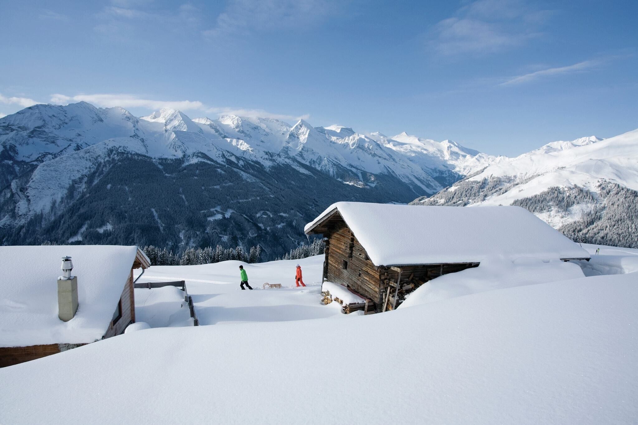 A snow-covered mountain landscape with a wooden cabin and a person in green attire.