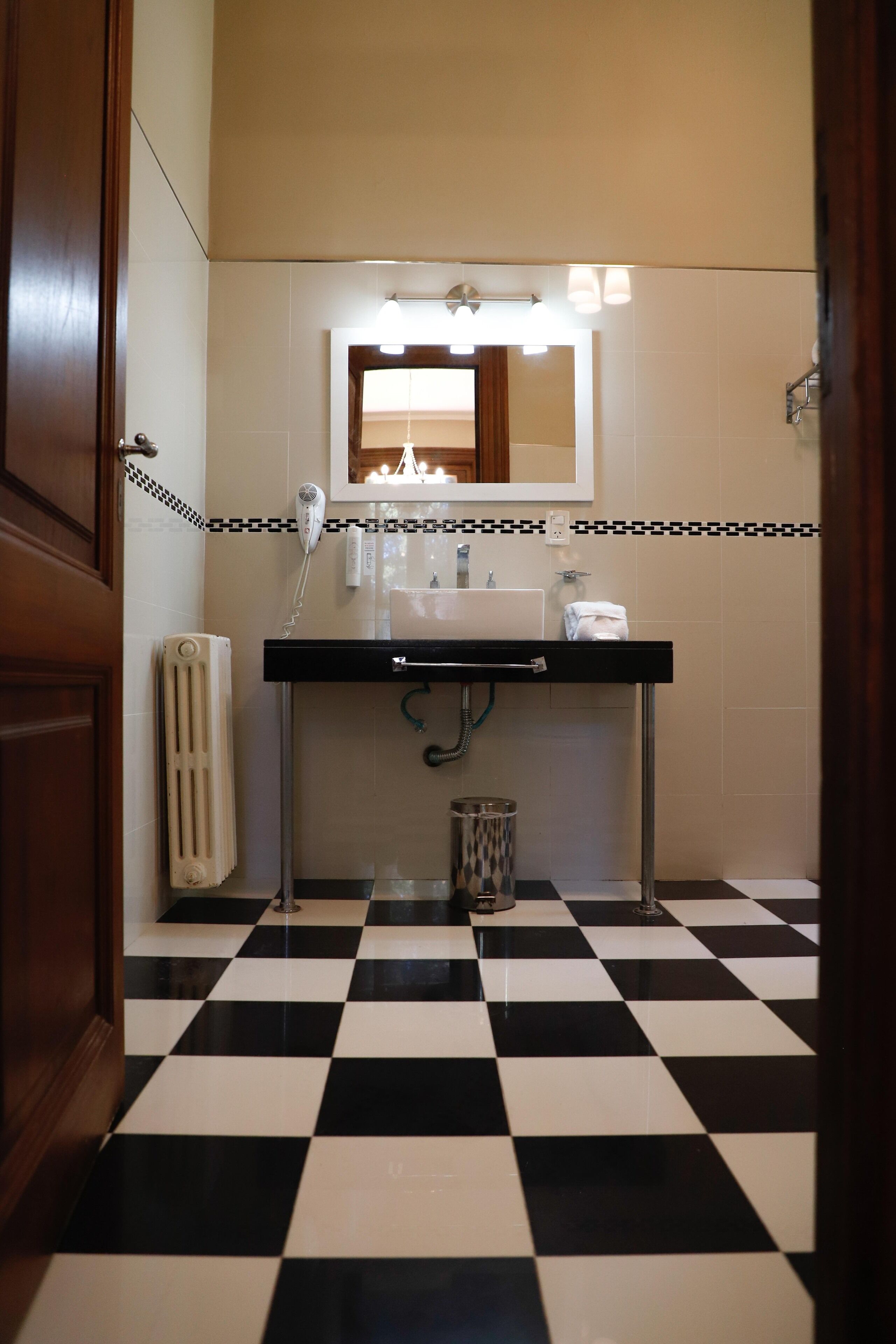 A bathroom with a black and white checkered floor, a sink with a mirror above it, and a towel hanging on the wall.