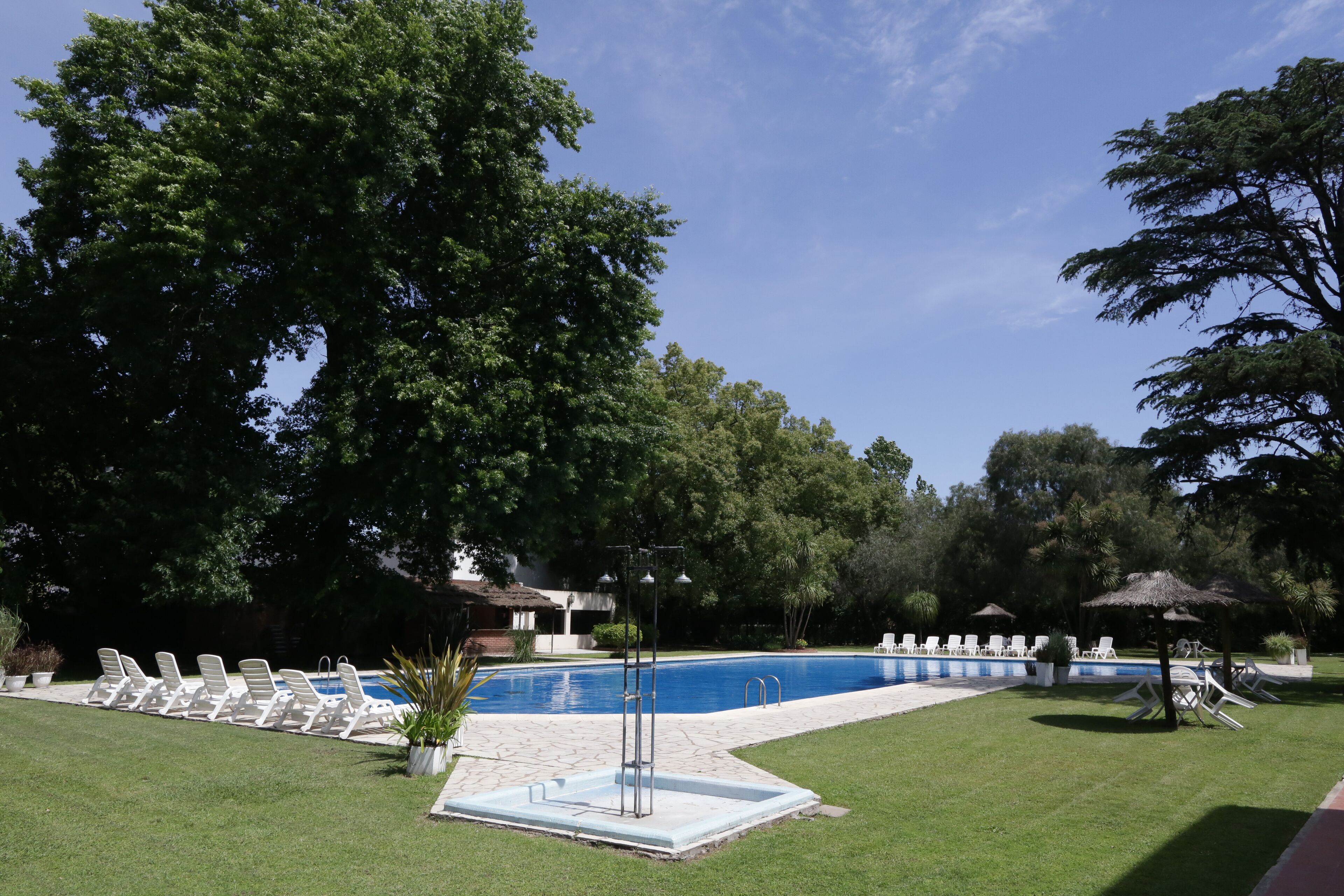 Une piscine dotée de chaises longues et d’un petit espace de terrasse, le tout entouré d’arbres.